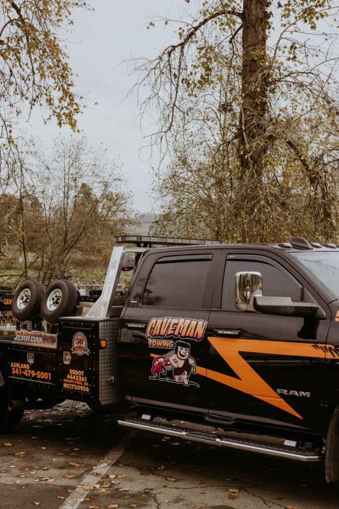 Caveman Towing logo and phone number on a light-duty wrecker